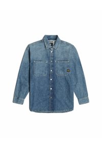 Denimblå långärmad skjorta med knäppning framtill, två bröstfickor och en liten svart och gul patch på höger ficka.