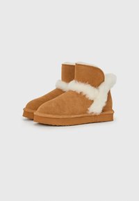 Bottines en daim marron avec un doux revers en fausse fourrure blanche, présentant un bout rond et une semelle en caoutchouc plate.