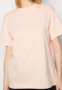Pink cotton T-shirt featuring a round neckline, short sleeves, a relaxed fit, and a small white Nike logo on the chest.