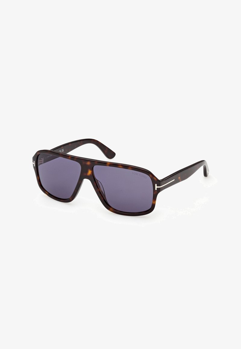 Lunettes de soleil rectangulaires en écaille de tortue avec des montures épaisses et des verres foncés, posées en angle sur un fond blanc.