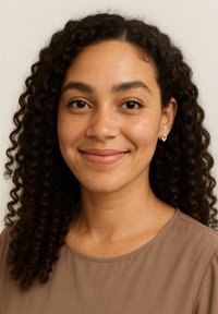 Kvinde med krøllet, mørkebrunt hår, iført en brun top. Hun har små blomsterøreringe og et naturligt makeup-look med et subtilt smil.