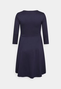 Vestido azul marinho com corpete ajustado e saia rodada, apresentando mangas longas e um decote redondo, confeccionado em um tecido suave e elástico.