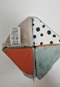 Flerfärgad tygkudde med geometriska sektioner i mjuka texturer: mintgrön, beige, prickig och rostorange. Tillverkarmärke fäst.