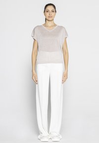 Jasnoróżowa bluzka z krótkim rękawem i dekoltem w serek; przewiewny materiał. Połączona z białymi, luźnymi spodniami i białymi butami na slip.