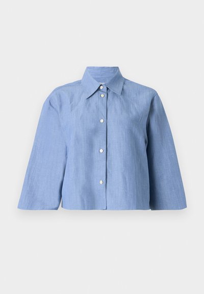 Light blue cropped shirt made of linen, featuring a pointed collar, button front, and three-quarter sleeves with a smooth texture.