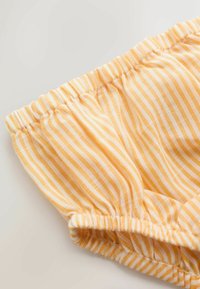 Tissu rayé jaune et blanc avec des bords élastiques, probablement une partie d'un vêtement tel que des shorts ou des bloomers.