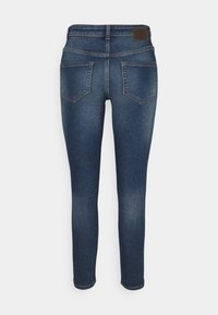 Slim fit jeans i mörkblå denim med medelhög midja, fyra fickor och subtila blekningar längs benen. Läderlappar vid midjan.