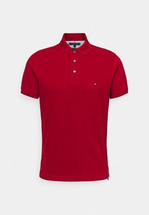 Rotes kurzärmeliges Poloshirt mit Drei-Knopf-Leiste und kleinem besticktem Logo auf der linken Brust.