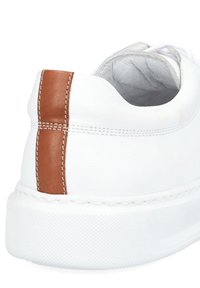 Białe skórzane sneakersy z brązowym akcentem na pięcie, teksturowana gumowa podeszwa i białe przeszycia wzdłuż krawędzi.