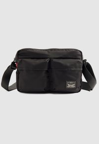 Juoda per petį nešiojama rankinė su dviem priekinėmis kišenėmis, reguliuojama diržele ir Levi Strauss & Co. logotipu apatiniame dešiniajame kampe.