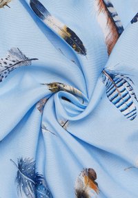 Tessuto blu chiaro con una consistenza morbida, caratterizzato da vivaci motivi di piume in vari colori tra cui marroni, blu e bianchi.