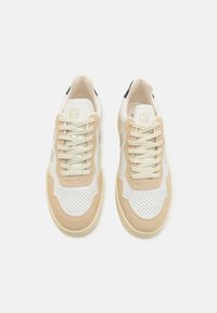 Weiße und beige Sneakers mit Wildleder- und Mesh-Materialien, durchbrochener Detailgestaltung und flachen Schnürsenkeln, die ein Logo auf der Zunge und der Ferse tragen.