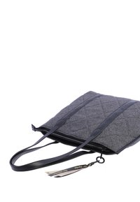 Bolsa tote de tela acolchada gris con acentos de cuero negro, doble asa y cierre de cremallera. Presenta etiquetas decorativas adjuntas.