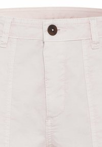 Pantalon en coton rose clair avec fermeture à bouton, passants pour ceinture et poches avant avec détails de coutures apparentes. Texture lisse et design ajusté.