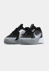 Fekete és szürke sportcipők textúrált felsőrésszel, háromszögletű kivágásokkal, fehér részletekkel és átlátszó talppal. Fűzős kialakítás és húzószalagok jellemzik.