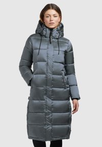 Abrigo largo acolchado en gris oscuro con un acabado brillante, capucha, cordón ajustable, cierre con cremallera y bolsillos laterales. Presenta un diseño acolchado.