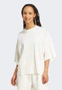 White oversized t-shirt with short sleeves, round neckline, and a smooth texture, paired with matching shorts.