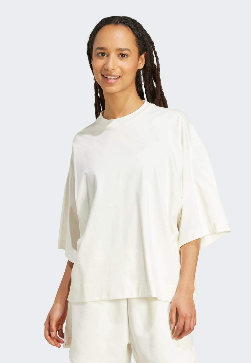 White oversized t-shirt with short sleeves, round neckline, and a smooth texture, paired with matching shorts.