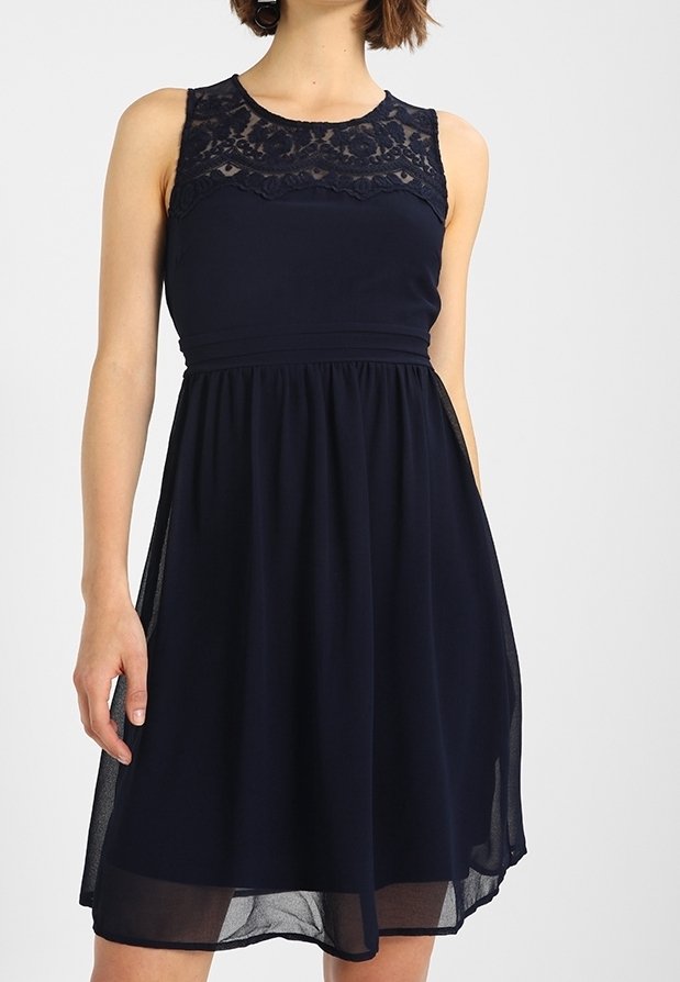 Mörkblå klänning med ärmlös design, spetsdetaljer vid halslinningen, insydd midja och flödande kjol i lätt tyg.
