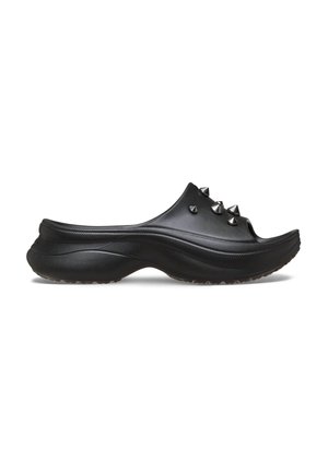 Schwarze Clogs mit glatter Oberfläche, ausgestattet mit fünf metallischen Spitzen oben. Die Sohle ist konturiert und hat eine strukturierte Grifffläche für Stabilität.