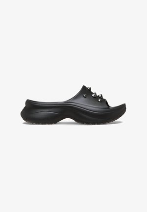 Black clogs with a smooth finish, featuring five metallic spikes on the upper. The sole is contoured with a textured grip for stability.