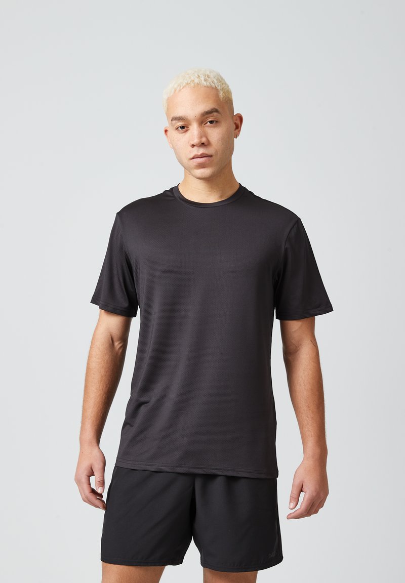 Maglietta sportiva nera a maniche corte, in tessuto leggero con una sottile trama, abbinata a pantaloni corti neri coordinati. Design semplice e funzionale.