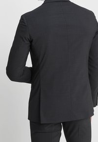 Dunkelgrau maßgeschneiderte Sakko mit glatter Textur, Reverskragen und einem Schlitz hinten. Verfügt über minimalistische Nähdetails.