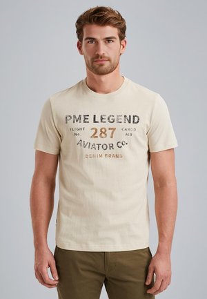 Bež majica s kratkim rukavima od pamuka, s okruglim izrezom, koja ima otisnuti grafički natpis u crnoj i smeđoj boji: "PME LEGEND FLIGHT br. 287 AVIATOR CO. DENIM BRAND."