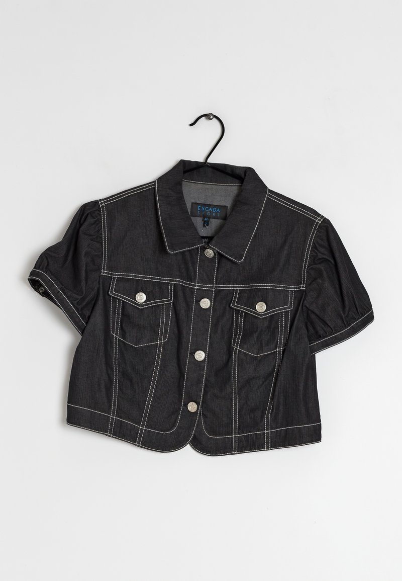 Musta lyhyt farkkutakki, jossa on lyhyet pussihihaiset hihat, valkoiset kontrastitikkausompeleet, hopeiset napit, läppätaskut ja klassinen kaulus henkarissa.