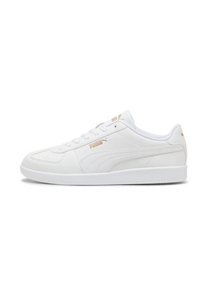 Sneaker bianco Puma low-top con logo dorato, dettagli di cucitura e suola testurizzata, mostrata in profilo laterale su sfondo bianco.