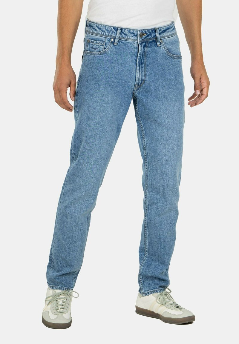 Jeans de mezclilla azul claro con un diseño de pierna recta, que cuentan con una cremallera, estilo de cinco bolsillos y un ligero desteñido, combinados con zapatillas blancas.