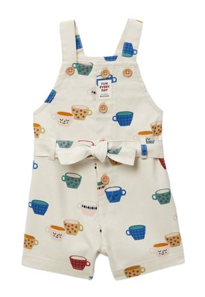 Salopette courte pour tout-petit de couleur crème avec des motifs de tasses colorées, des boutons en bois, et une ceinture en tissu nouée à la taille.