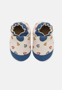 Zapatos de cuero para bebés con un upper crema que presenta coloridos patrones de peces. Punta de goma azul oscura y tobillo elástico para un ajuste seguro.