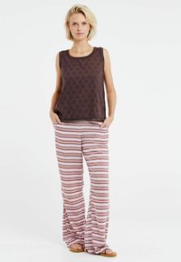 Top sin mangas marrón con patrón de diamantes y pantalones holgados a rayas en rojo, blanco y burdeos con forma acampanada y bolsillos.