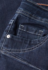 Jeans in denim scuro con tasca frontale decorata da rivetti in metallo argentato. Cuciture bianche distintive e superficie liscia.