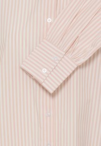 Garām piedurknēm krekls gaiši rozā un krēmkrāsas vertikālās svītrās, ar pogājamu aproci un baltām pogām gar pogu līniju. Gluda auduma tekstūra.