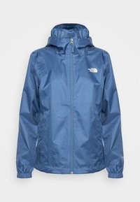 Veste imperméable bleue avec capuche, fermeture éclair frontale, poignets élastiques et logo blanc The North Face sur la poitrine gauche.