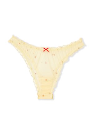 Tanga de color amarillo pálido translúcido con pequeños estampados de frutas, bordes con volantes y un pequeño lazo rojo en el centro de la cinturilla frontal.