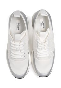 Białe sneakersy z materiału z fakturą, szare akcenty na pięcie i białe sznurowadła. Zawierają logo z boku oraz wyściółkę na języku.