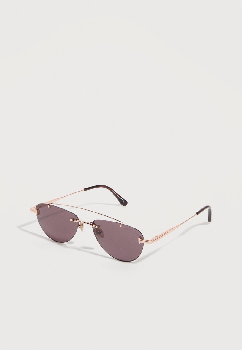 Sleek sunglasses with thin rose gold metal frame and dark tinted oval lenses, resting on a white surface.