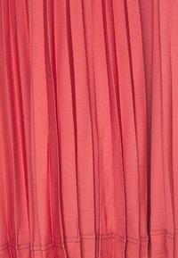 Tessuto plissettato corallo con una texture setosa. Le pieghe verticali creano un design fluido, rifinito con cuciture delicate lungo l'orlo.