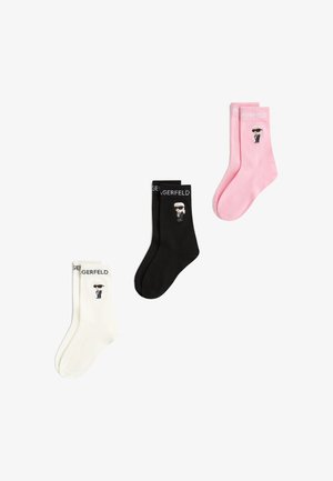 Trois paires de chaussettes Karl Lagerfeld en blanc, noir et rose, chacune avec une figure cartoon de Karl Lagerfeld et un logo sur le bord-côte.