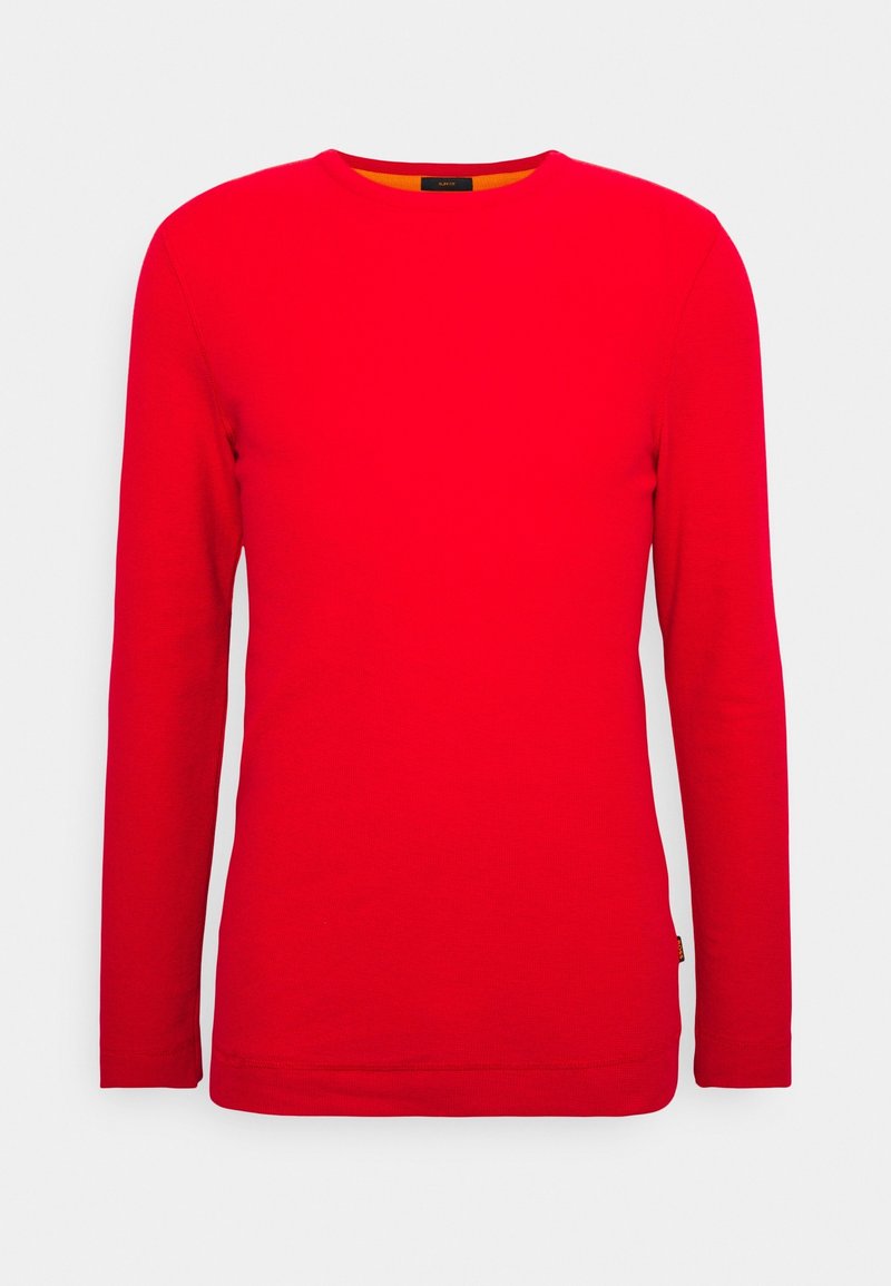 T-shirt rouge uni à manches longues et col rond avec une petite étiquette sur le côté inférieur, présenté sur fond blanc.