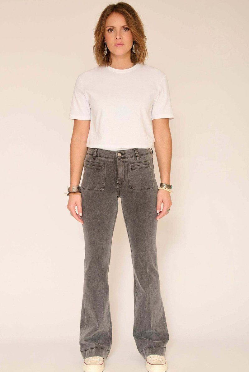 Pantalon évasé en velours côtelé gris avec poches avant, accompagné d'un t-shirt blanc uni à manches courtes et de baskets de couleur claire.