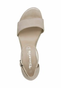 Beige mockasinsandal med ett brett band över tårna, justerbart vristband och en slät lädersula. Platt sula design.