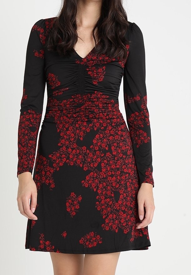 Robe noire à manches longues avec un décolleté en V froncé et un motif floral rouge. Jupe évasée atteignant le mi-cuisse. Texture de tissu lisse.