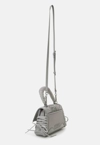Sac bandoulière gris en matériaux maillés et en cuir, poignée incurvée unique, détail lacé et bandoulière réglable.