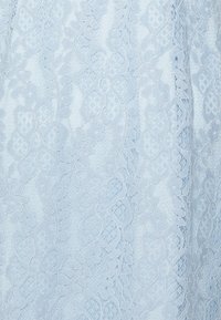 Tissu en dentelle bleu clair présentant des motifs floraux, des détails complexes et une texture douce. Le design comprend des tissages ouverts et des bords délicats.