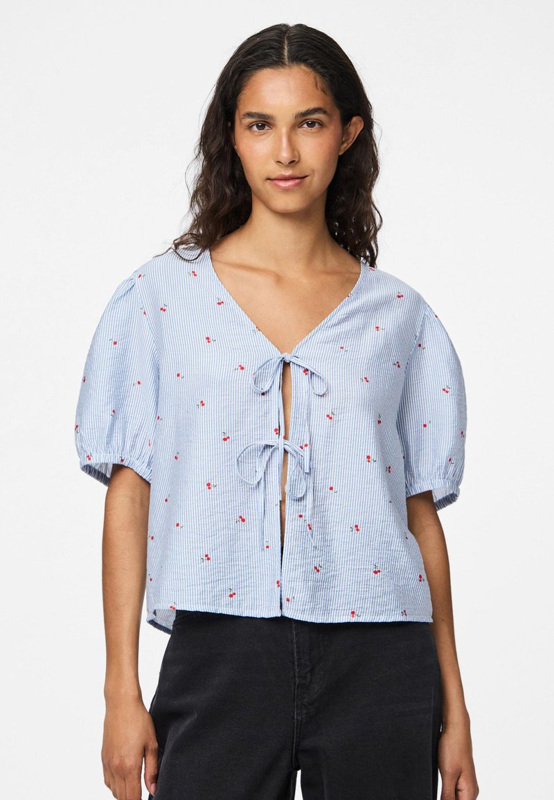 Blue and white striped blouse with puff sleeves, v-neckline, and red floral embroidery. Features a tie closure at the front.