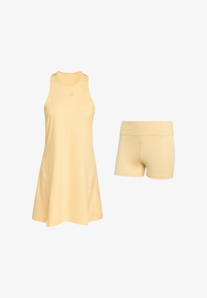 Gul atletik kjole med ærmeløs design, rund halsudskæring og blødt stof. Kombineret med matchende gule shorts.